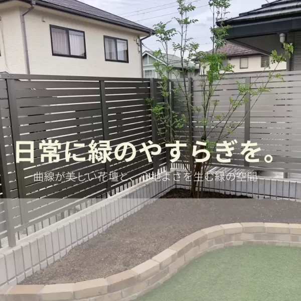 人工芝と曲線のレンガ花壇が整った庭の施工途中の様子。整然とした緑の空間が広がる